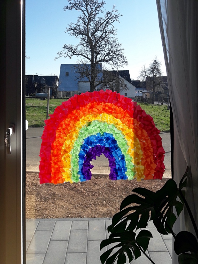 Grafik: Regenbogenbild an Fenster geklebt.