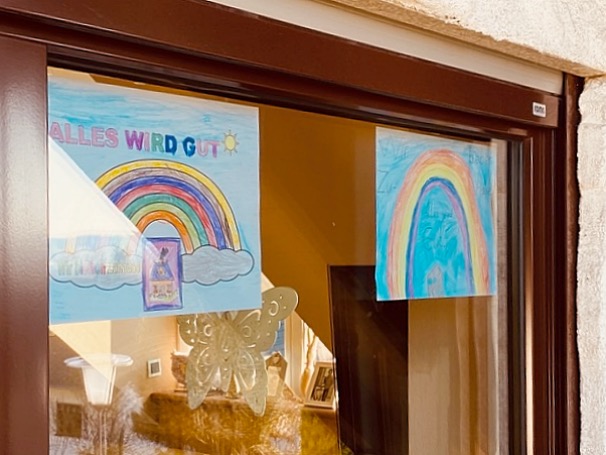 Grafik: Mehrere Regenbogenbilder an Fenster geklebt. 