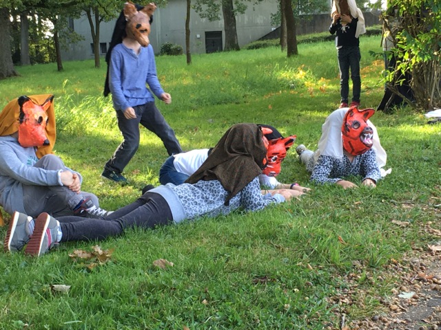 4 Kinder mit roten Tiermasken liegen auf dem Boden